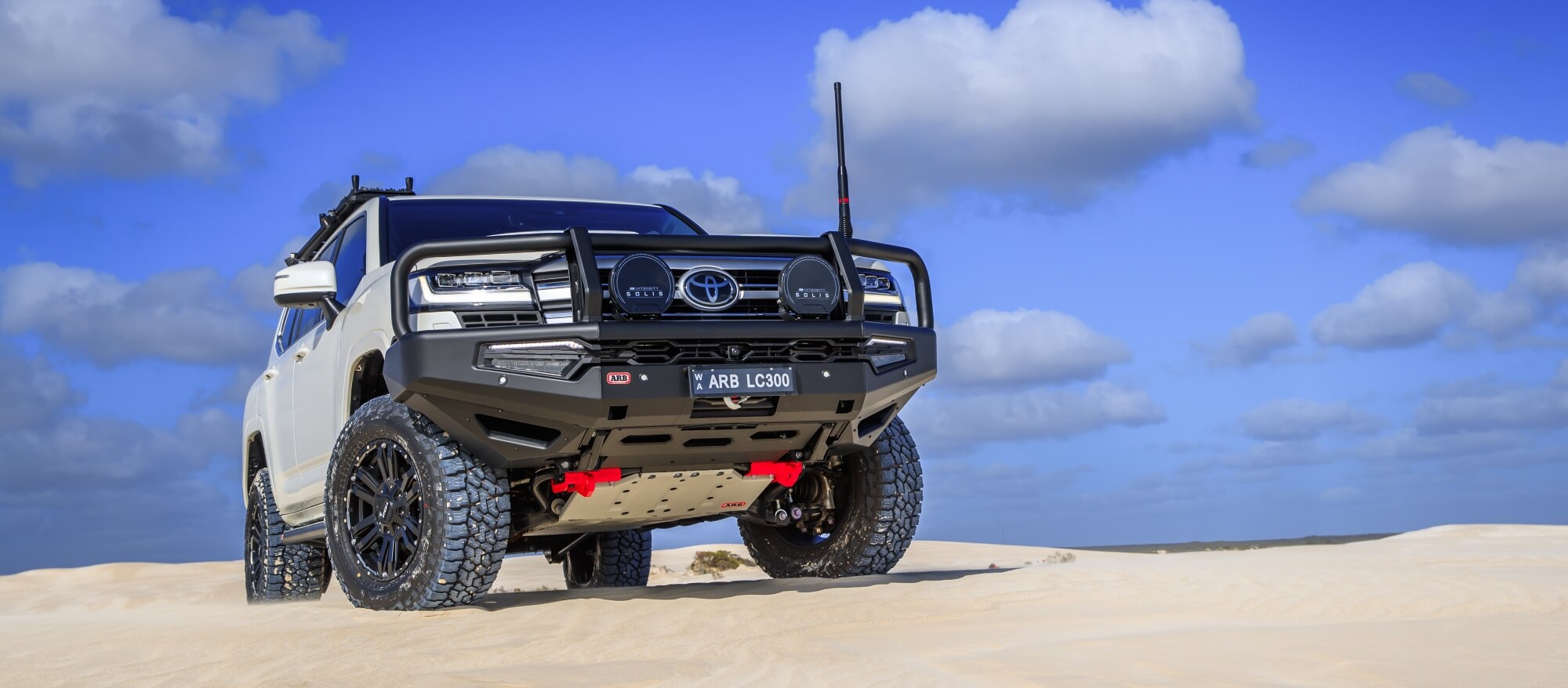 ARB Toyota Landcruiser on a sandy hill showing the Intensity Solis Spot and Flood mounted on the vehicles Bullbar with Black Accessory Covers used